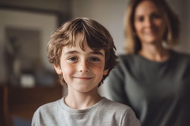 Lächelnder Junge mit Mutter im Hintergrund
