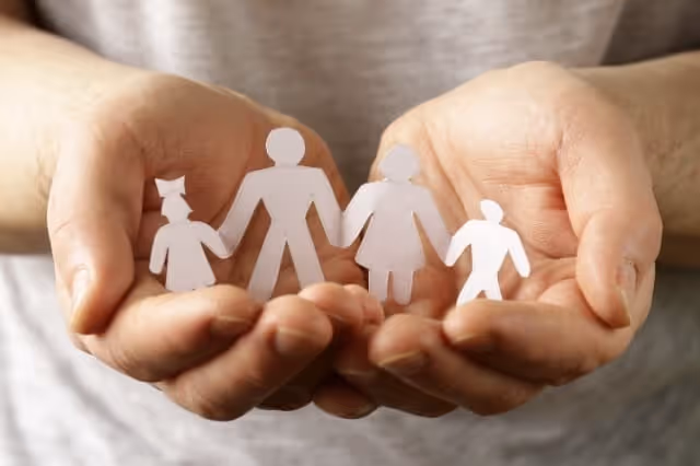 Hände halten Familie aus Papierfiguren