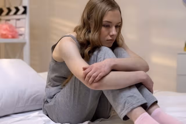 Depressives Mädchen sitzt traurig auf dem Bett