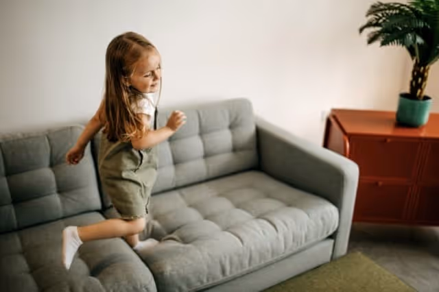 Kind springt fröhlich auf dem Sofa