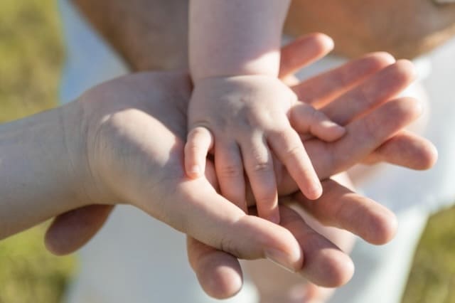 Babyhand liegt auf Elternhänden