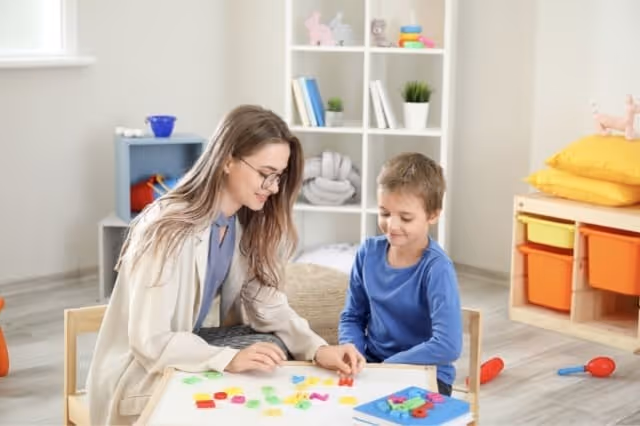 Kindertherapeutin spielt mit Kind im Therapieraum