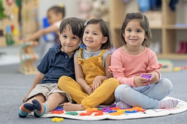 Kinder sitzen lachend im Kindergartenkreis