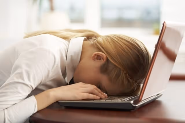 Mutter mit Burnout liegt mit Kopf auf Laptop