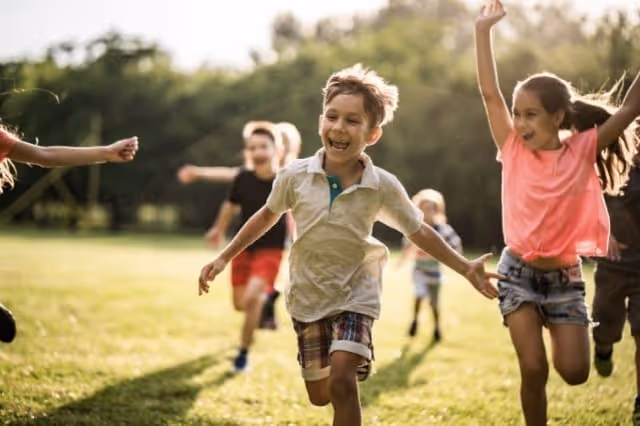 Kinder toben lachend auf einer Wiese