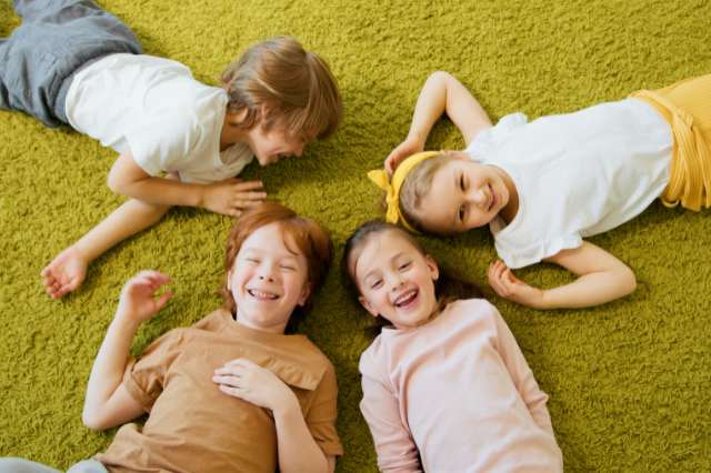 Resilienz bei Kindern: lachende Kindergruppe auf dem Teppich