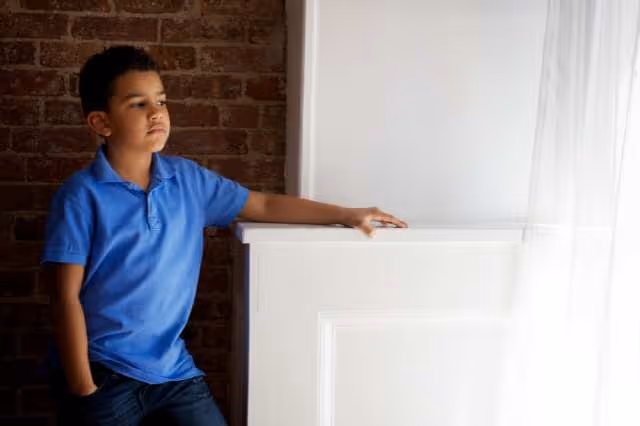 Nachdenklicher und trauriger Junge steht am Fenster