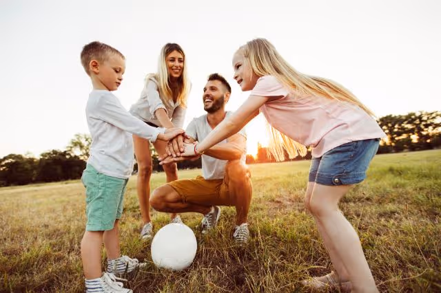 Eltern und Kinder spielen draußen mit dem Ball