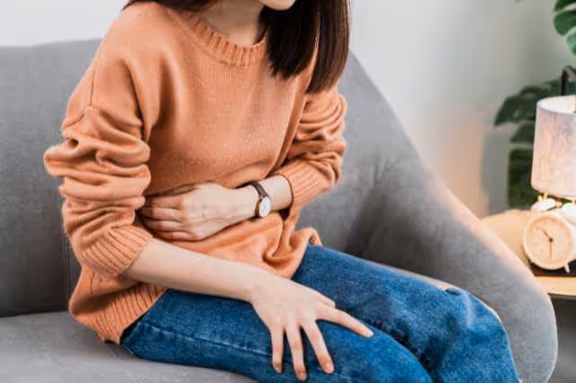 Frau umfasst den Bauch vor Schmerzen