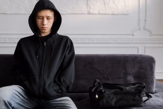 Nachdenklicher Jugendlicher sitzt allein auf dem Sofa