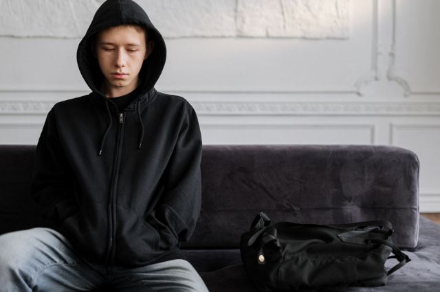 Nachdenklicher Jugendlicher sitzt allein auf dem Sofa