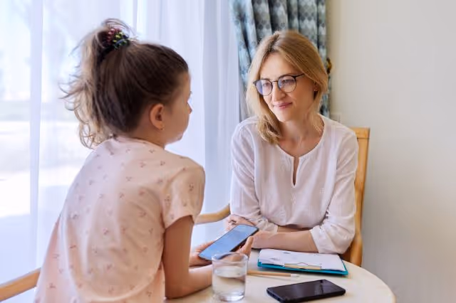 Mutter sitzt mit Kind am Tisch und lächelt