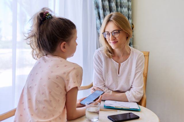 Mutter sitzt mit Kind am Tisch und lächelt