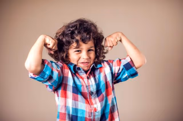 Kind demonstriert mit seinen Armen Stärke und Kraft