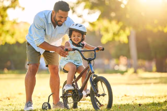 Vater bringt seinem Kind das Fahrrad fahren bei