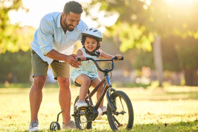 Vater bringt seinem Kind das Fahrrad fahren bei