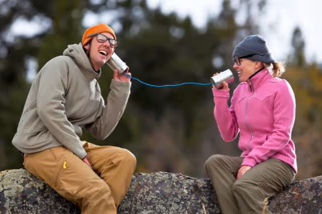 Zwei Personen kommunizieren über Blechdosen miteinander