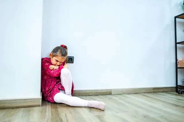 Kind sitzt traurig in einer Ecke