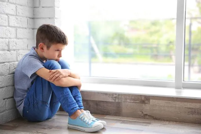 Kind sitzt traurig am Boden