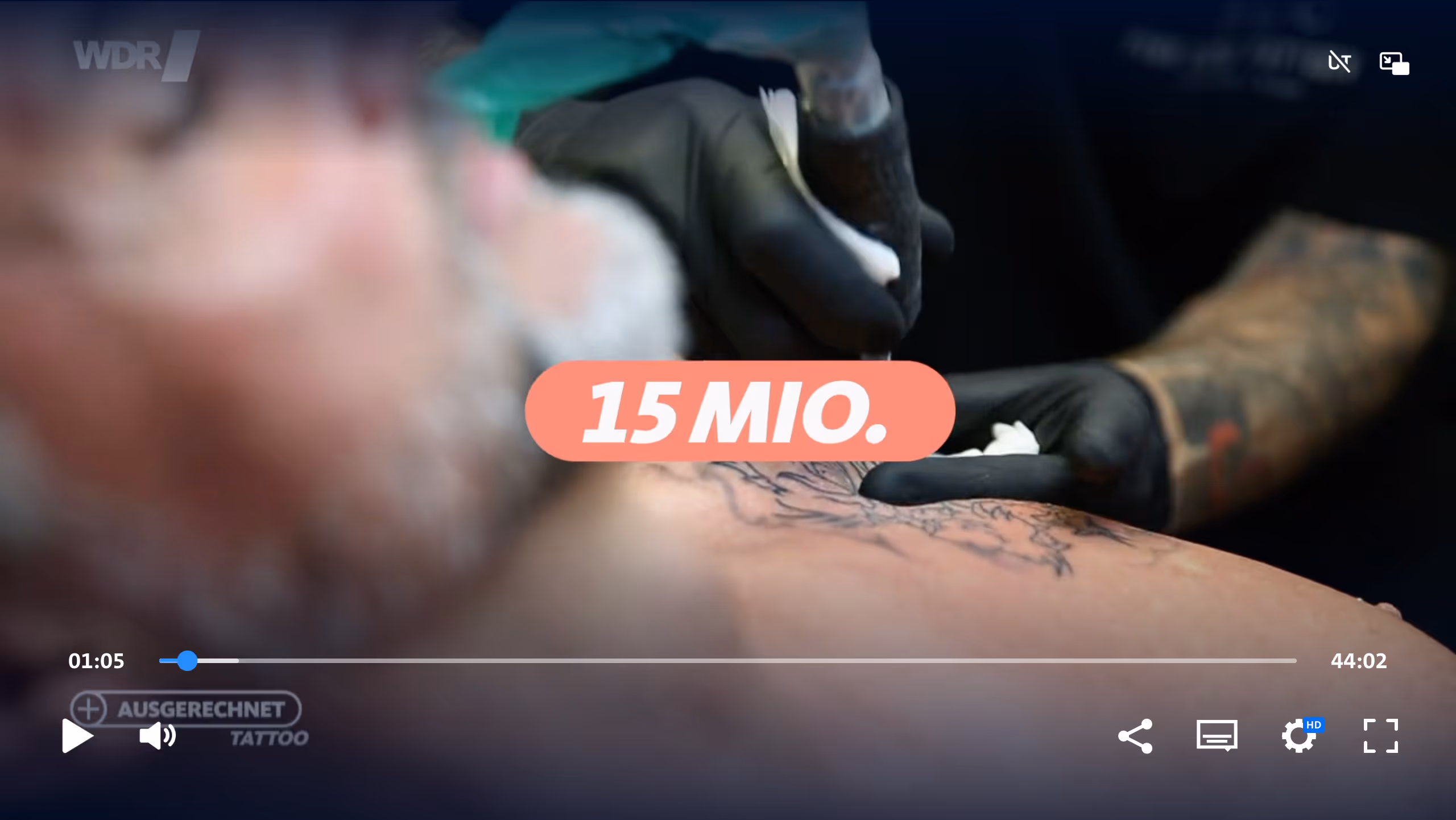 Nahaufnahme eines tätowierten Oberkörpers, während ein Tätowierer mit schwarzer Handschuh eine Tätowiermaschine benutzt.