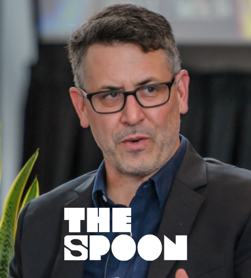 Hombre con cabello rizado y camisa blanca sonriendo, con fondo urbano desenfocado y logo de kfund.