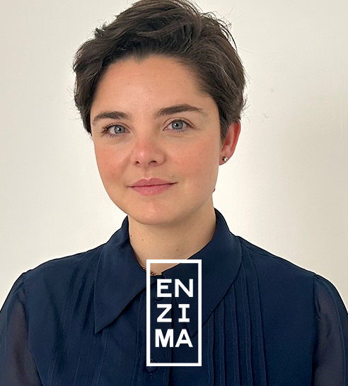 Mujer de cabello corto y oscuro sonriendo, vestida con blazer claro y pendientes de aro.