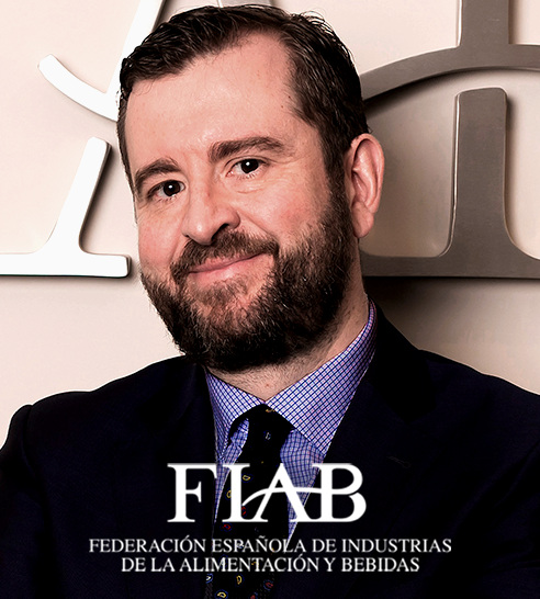 Mujer de cabello corto y oscuro sonriendo, vestida con blazer claro y pendientes de aro.