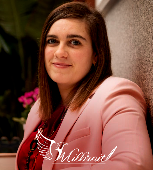 Mujer de cabello corto y oscuro sonriendo, vestida con blazer claro y pendientes de aro.