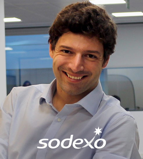 Mujer de cabello corto y oscuro sonriendo, vestida con blazer claro y pendientes de aro.