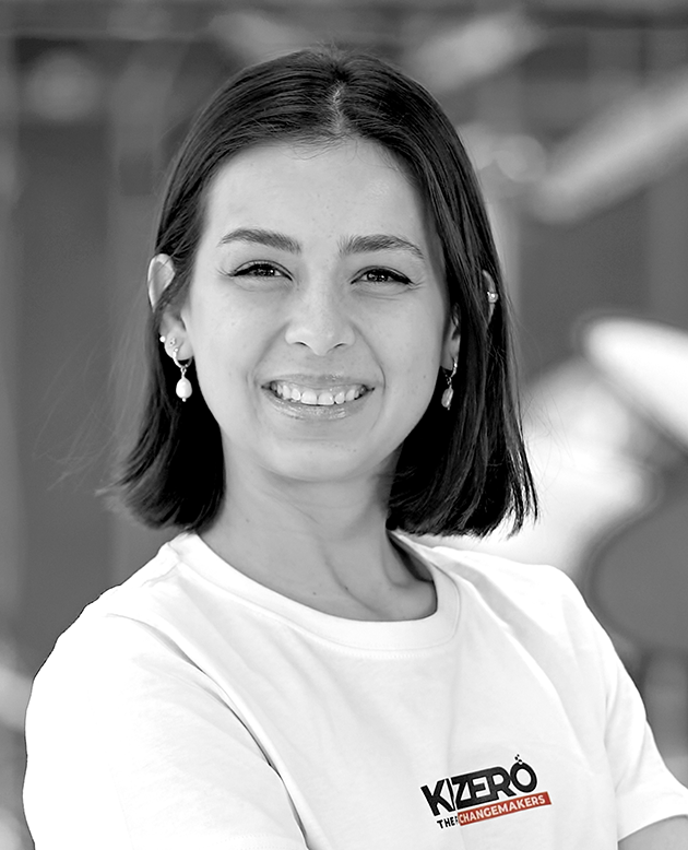 Retrato en blanco y negro de una mujer joven con cabello recogido, usando blazer de patrón de cuadros y pendientes de aro.