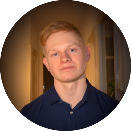 Young man with red hair in navy polo shirt smiling at camera