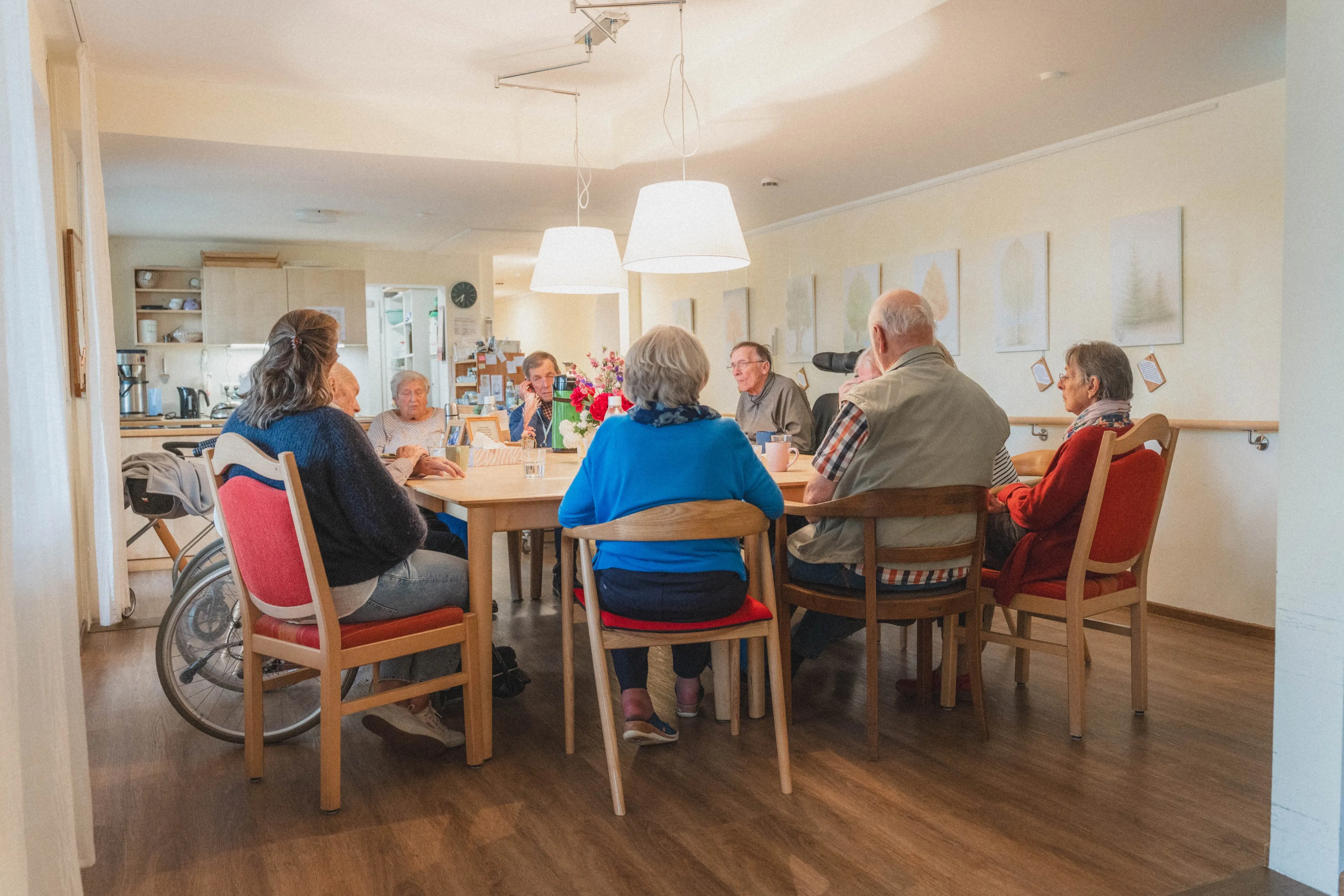 Ältere Menschen sitzen in einem hellen Raum gemeinsam an einem Tisch und unterhalten sich.