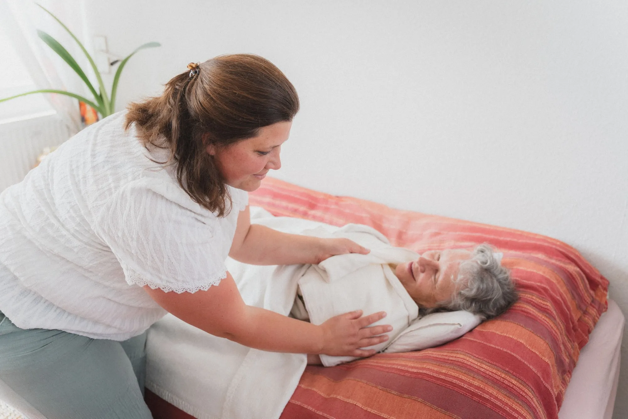 Pflegerin unterstützt Bewohnerin mit Wickel Auflagen.