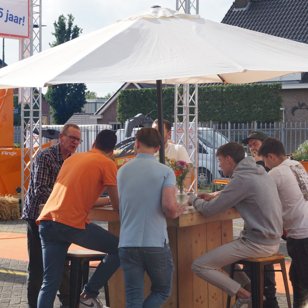Familiedag op bedrijf met parasol en mensen aan hangtafel