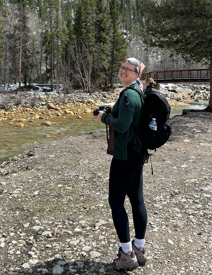 Photo of Alexa holding her camera in the mountains of Colorado