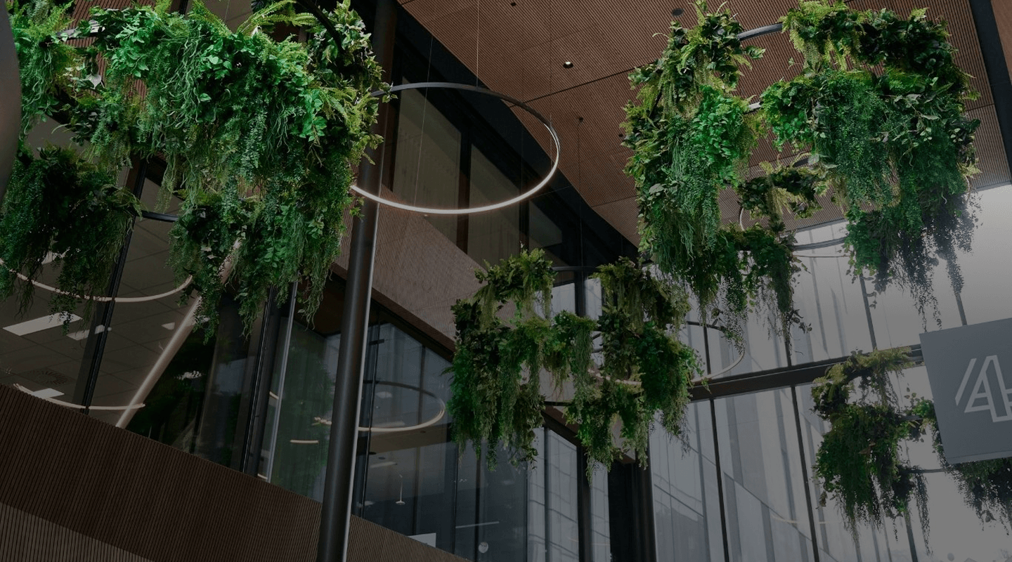 Suspended circular plant installations with cascading ferns and foliage hanging from a multi-storey atrium ceiling