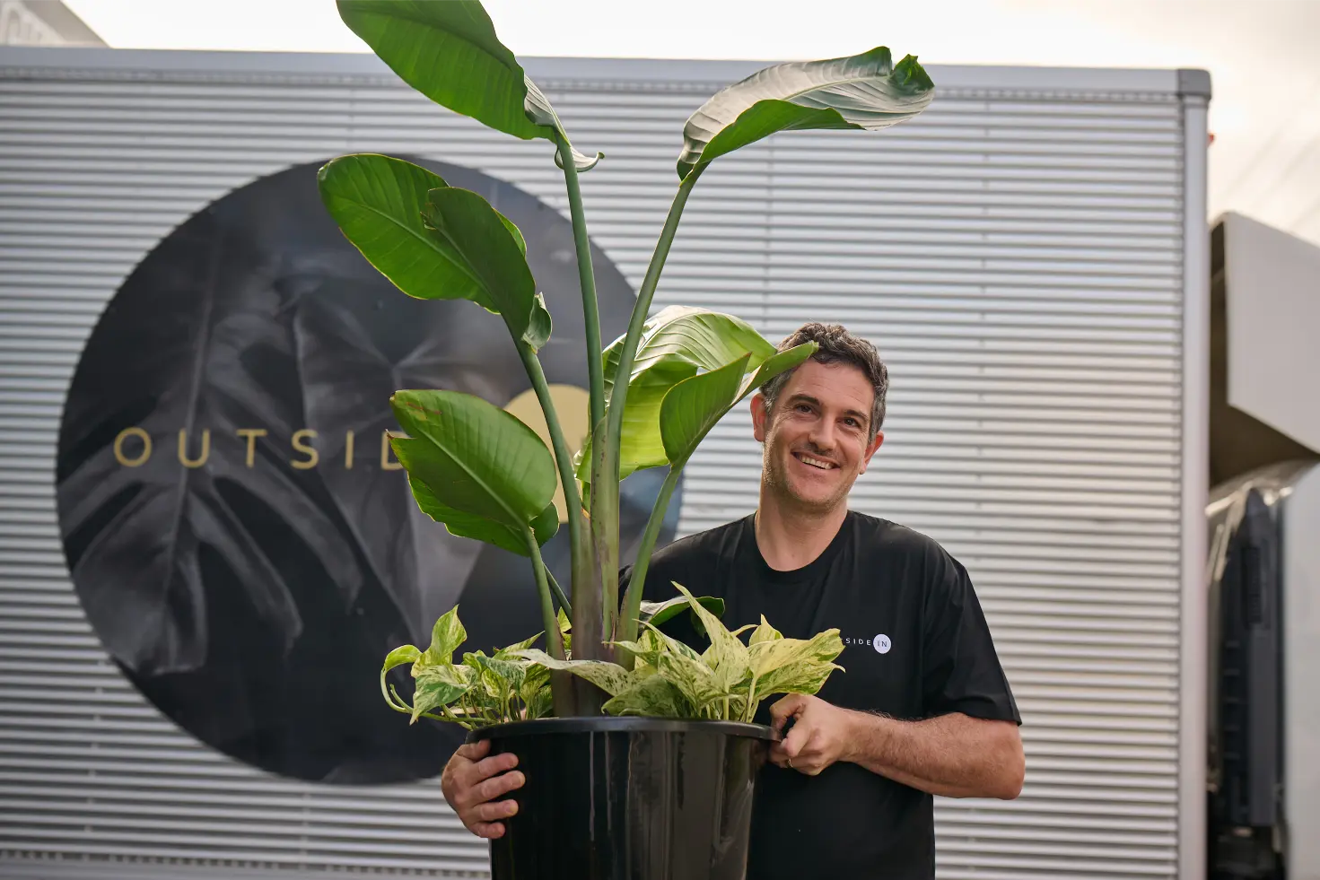 Outside In team member holding a bird of paradise plant ready for installation