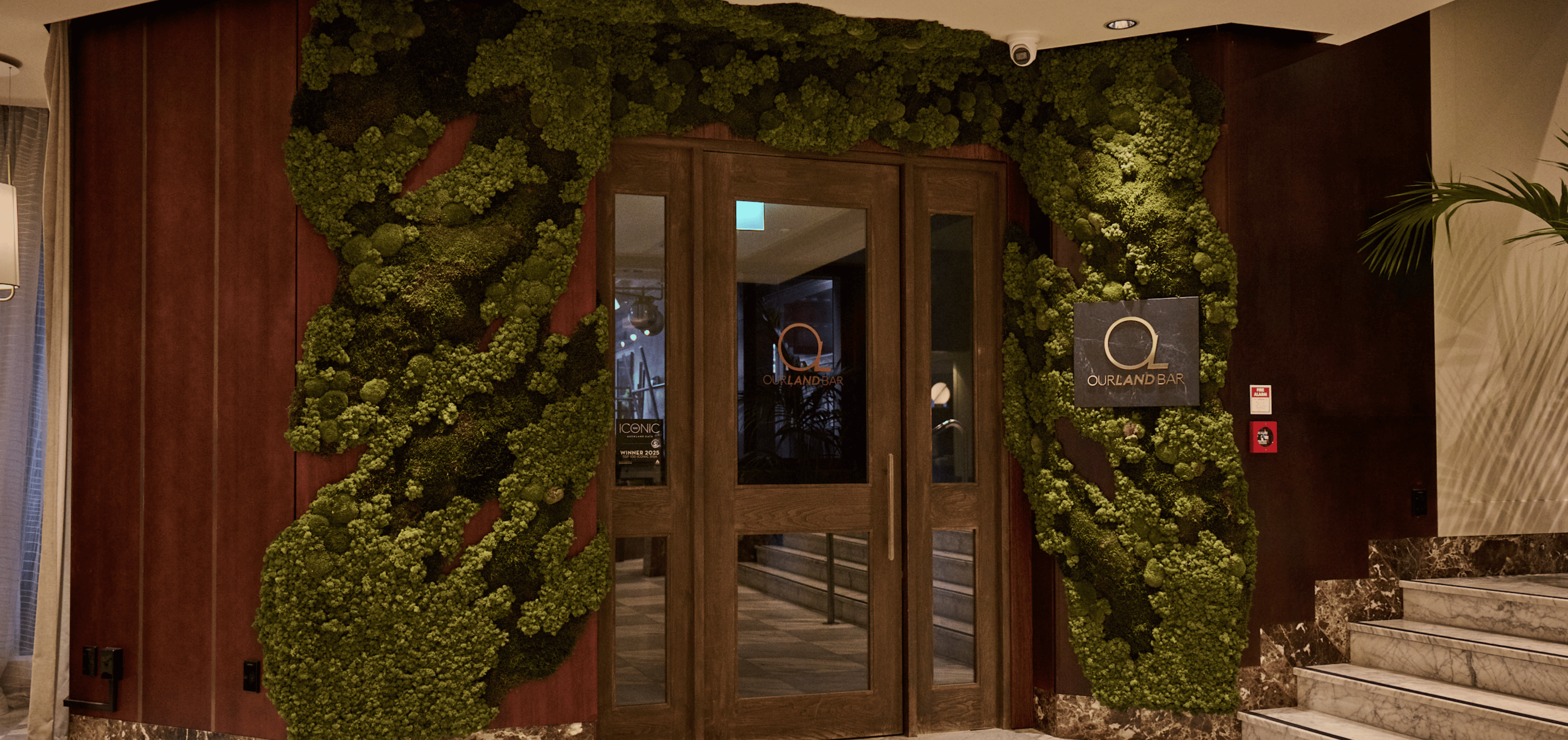 A sculptural moss installation transforming the entrance to Our Land Bar at Cordis Hotel.