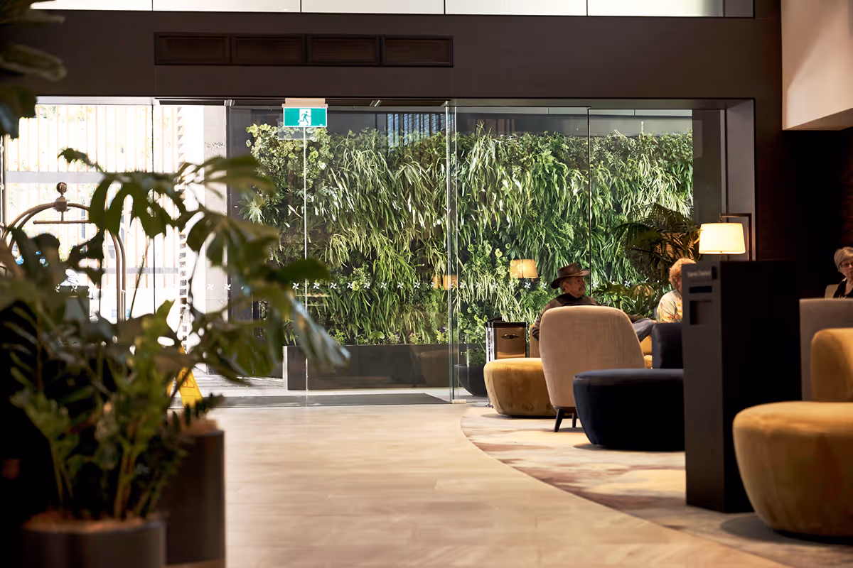 Floor-to-ceiling living green wall installed in a hotel lobby with lush tropical foliage as part of an Outside In hotel greenery design scheme