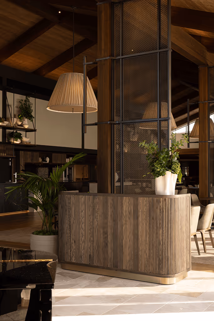 Luxury hotel reception desk with tropical indoor plants and warm timber architectural details, showcasing how biophilic greenery design enhances the hotel guest experience