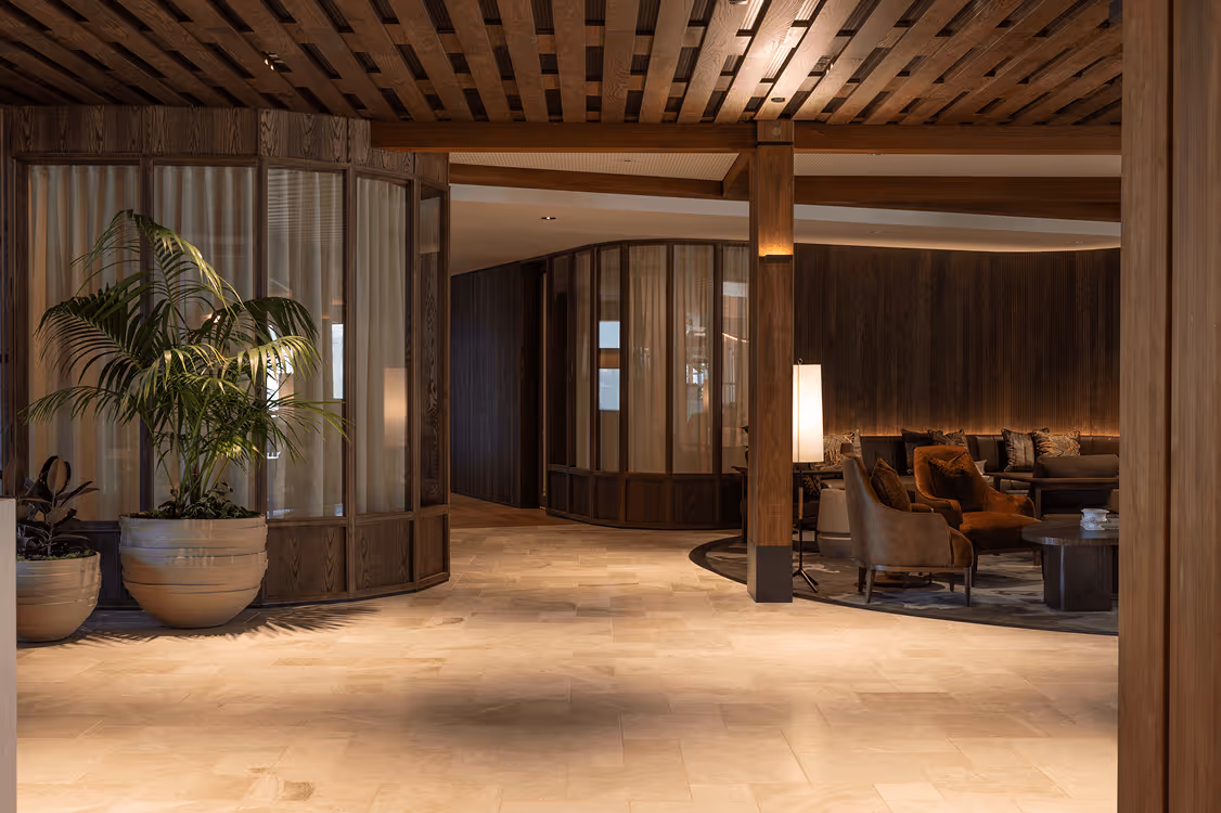 Warm and elegant later living lounge interior with palm planting and timber architectural details designed to create a homely, nature-connected environment