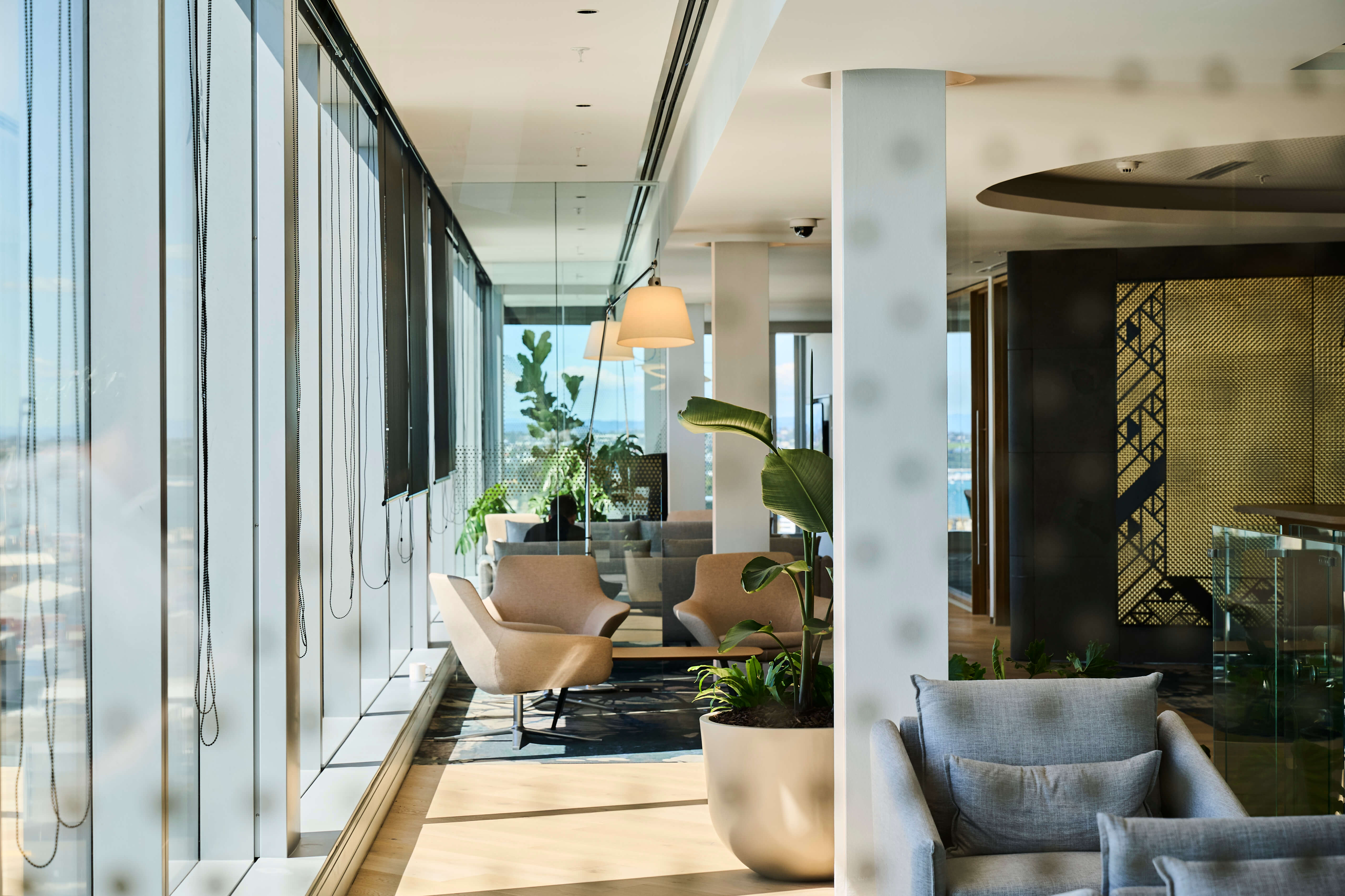 Bird of paradise in a round planter adds greenery to the Deloitte lounge, beside harbour views and a gold lattice screen.