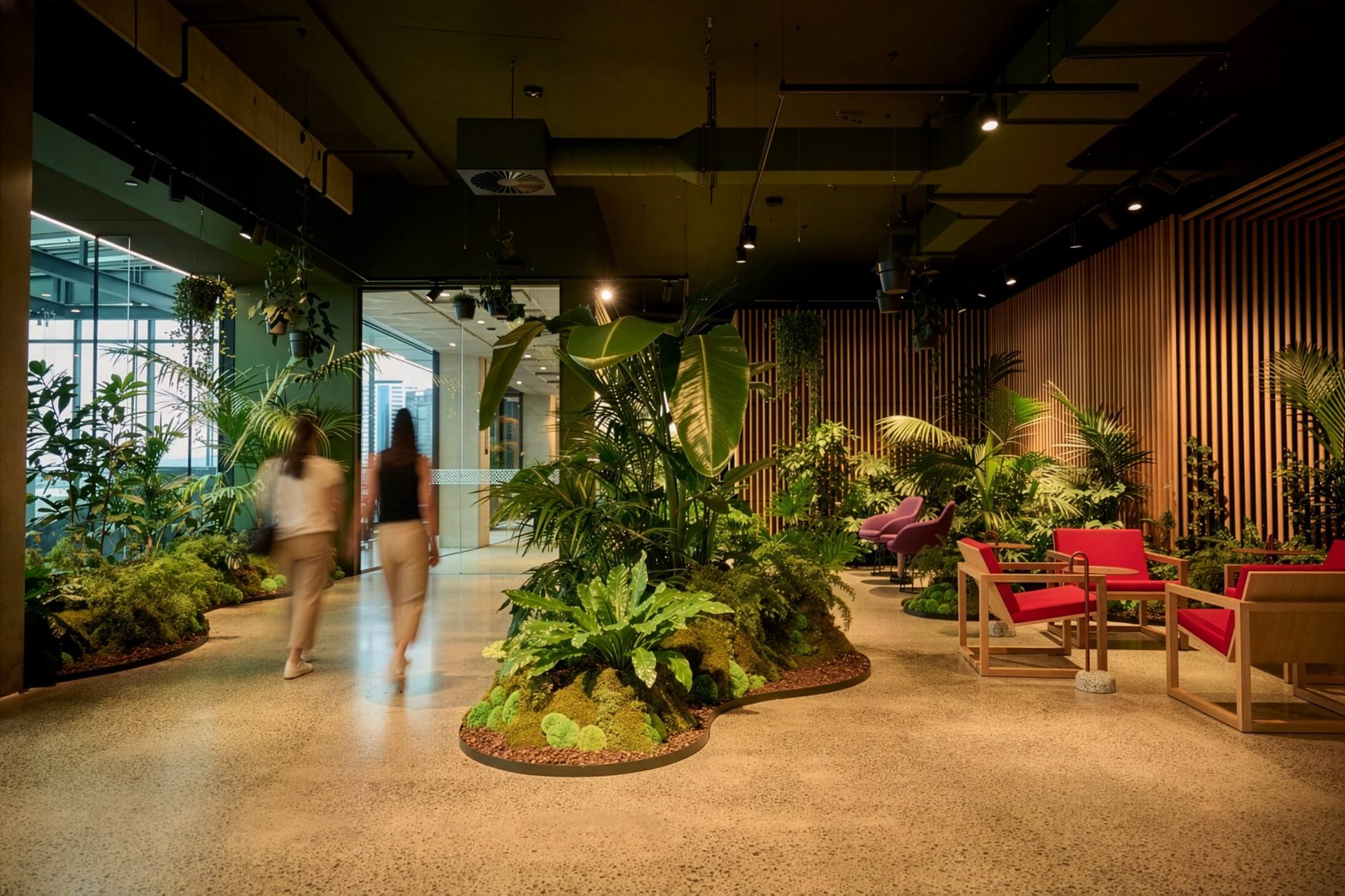 Island garden beds of palms, ferns, and moss fill the MC workspace — biophilic design embedded into the floor plan.