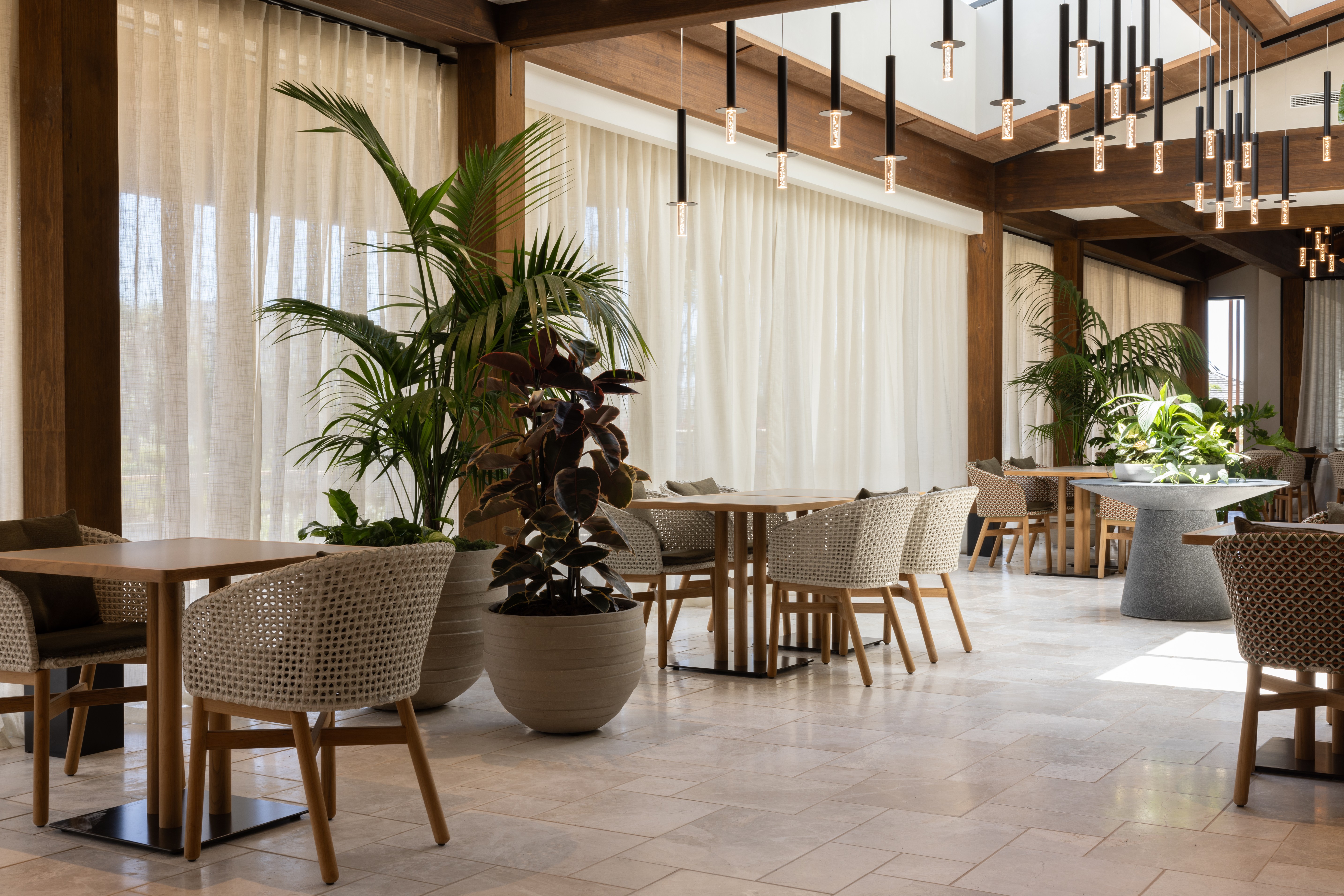 Kentia palm and a foliage arrangement beside a fluted timber bar counter with pendant lighting above.