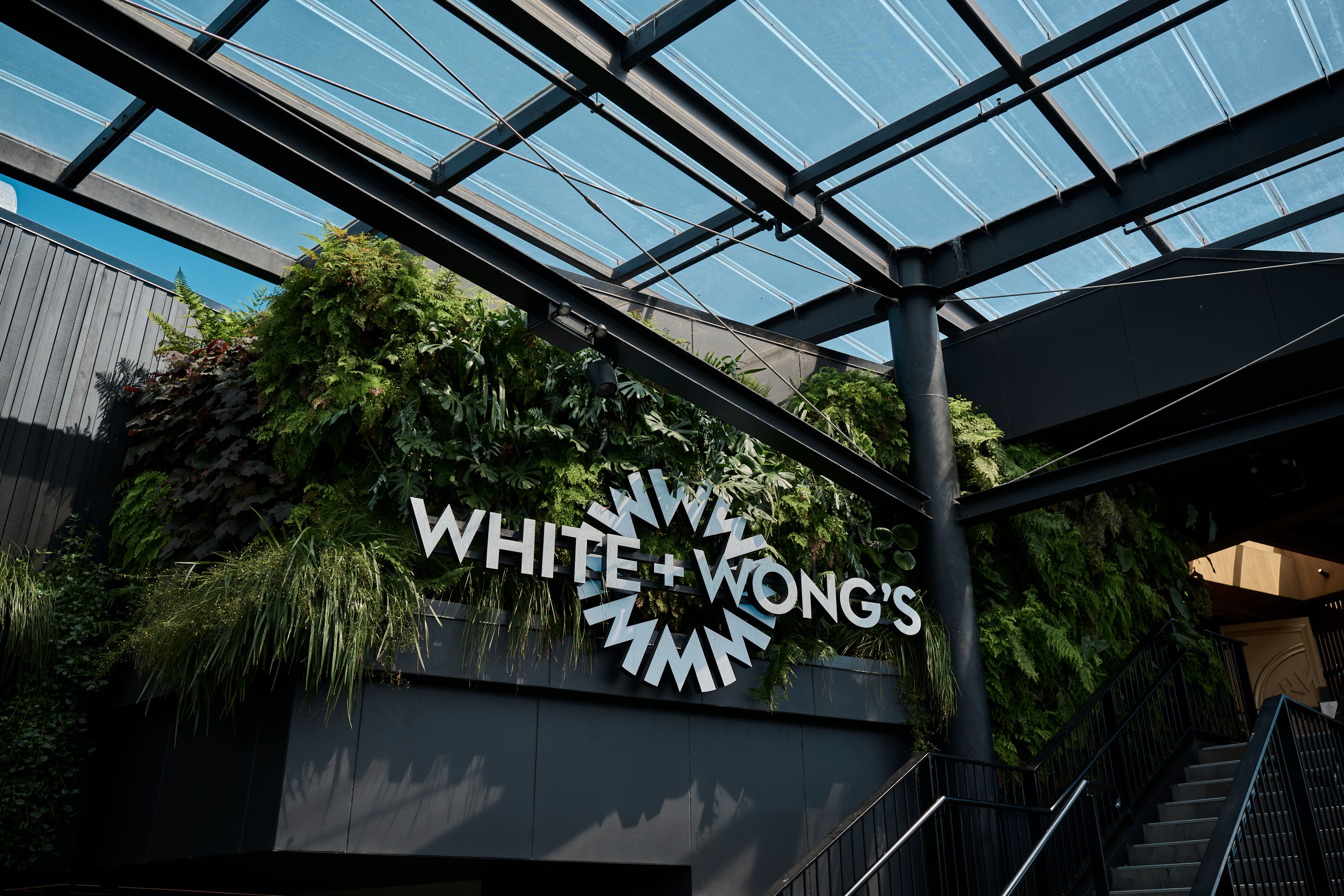 A lush living wall of ferns and tropical foliage frames the White + Wong's restaurant entrance at Westfield Newmarket.