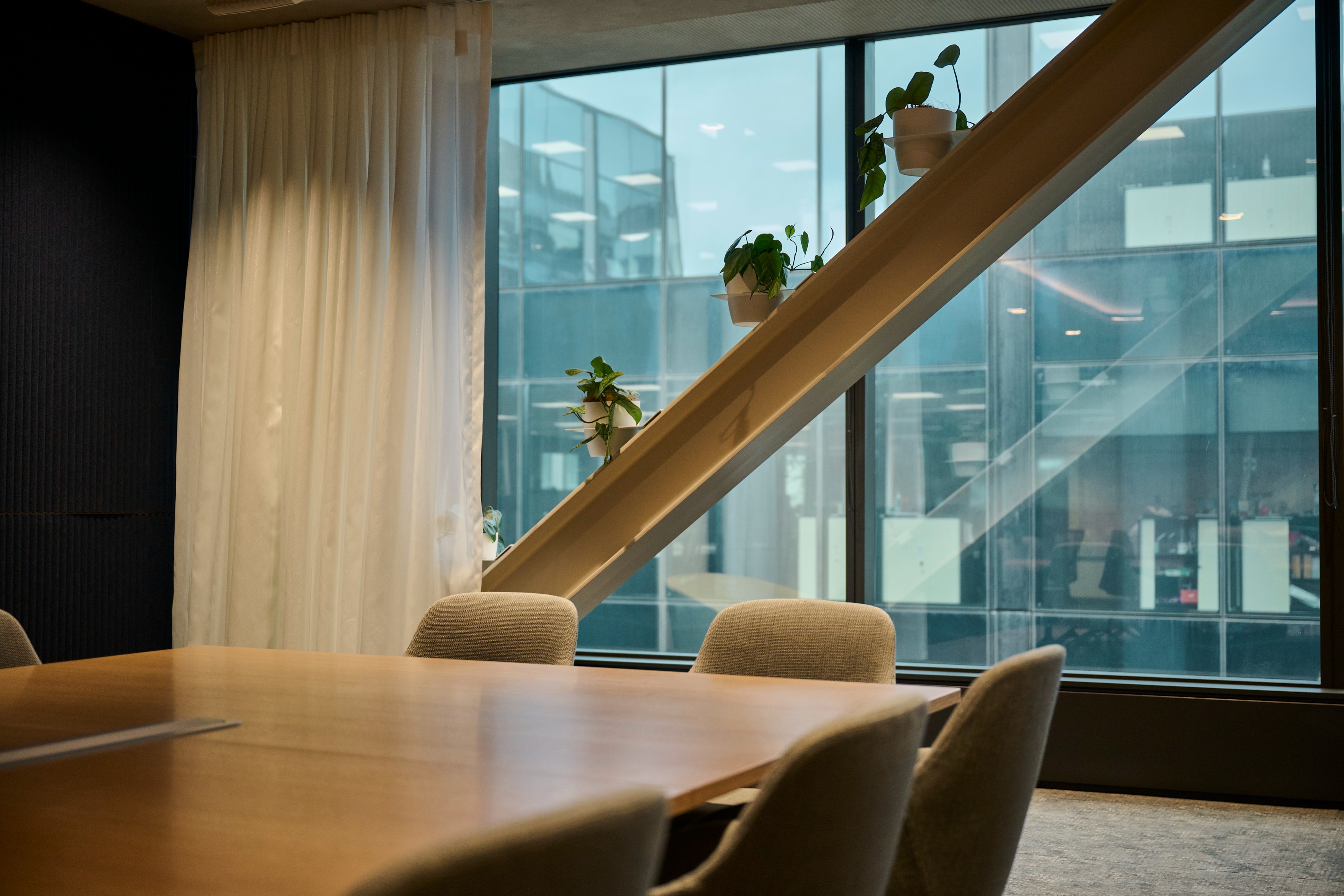 Small pothos plants on a diagonal timber ledge soften the dark meeting room at Simpson Grierson.