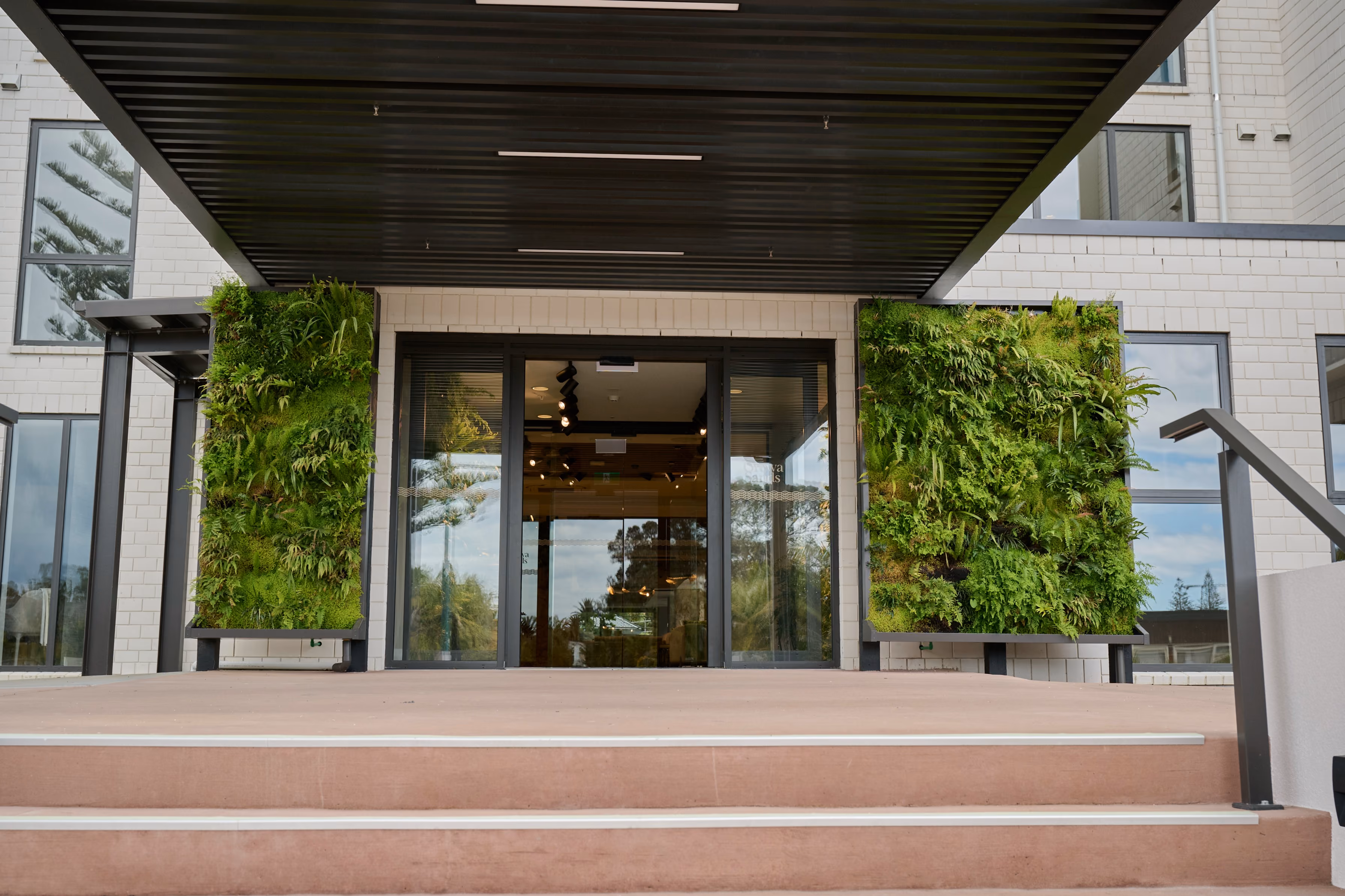 Orewa's entrance — living walls of ferns and tropical foliage flanking the glass entry doors.