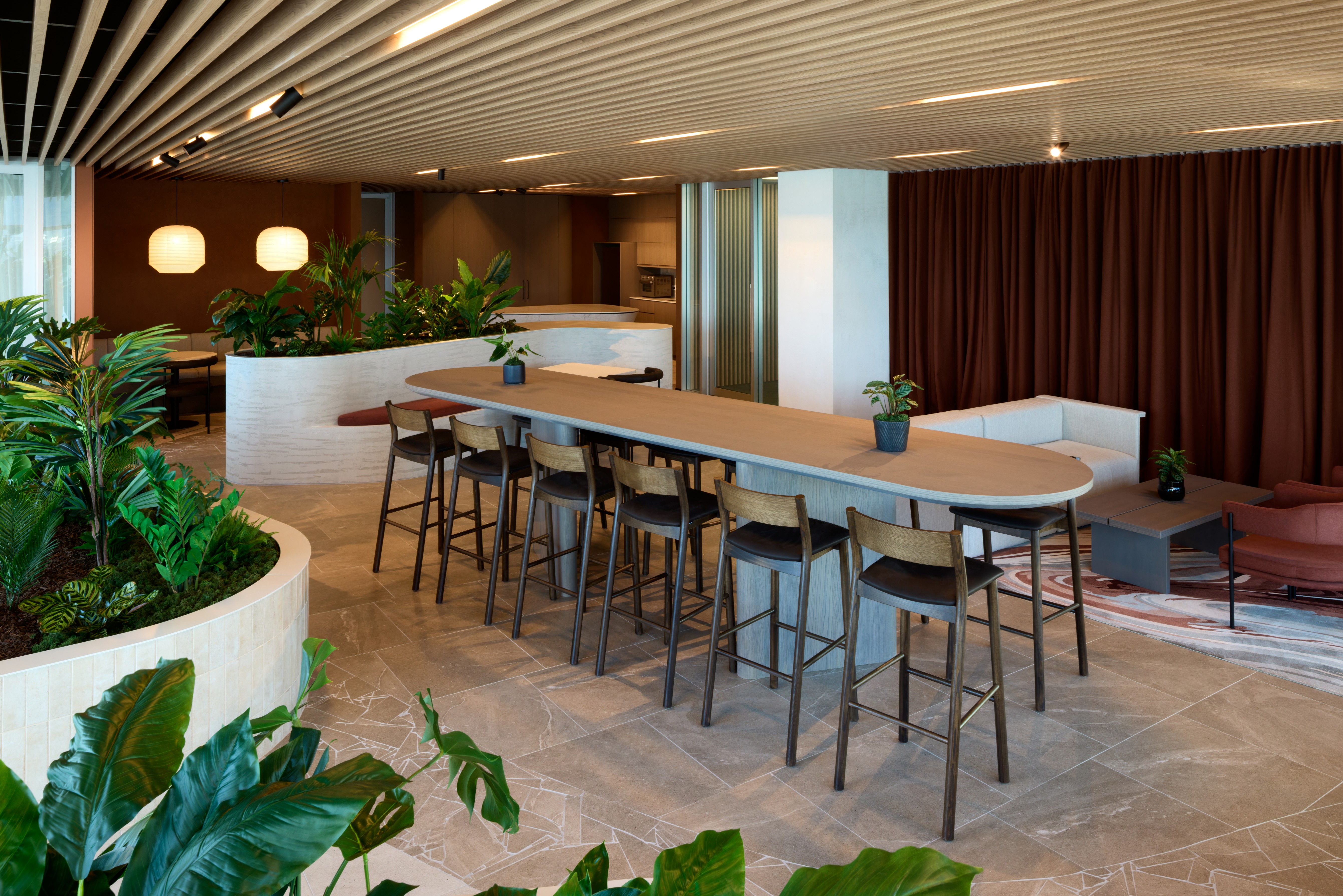 Sweeping curved planters of tropical foliage frame the SecuritEase breakout cafe and high bar.