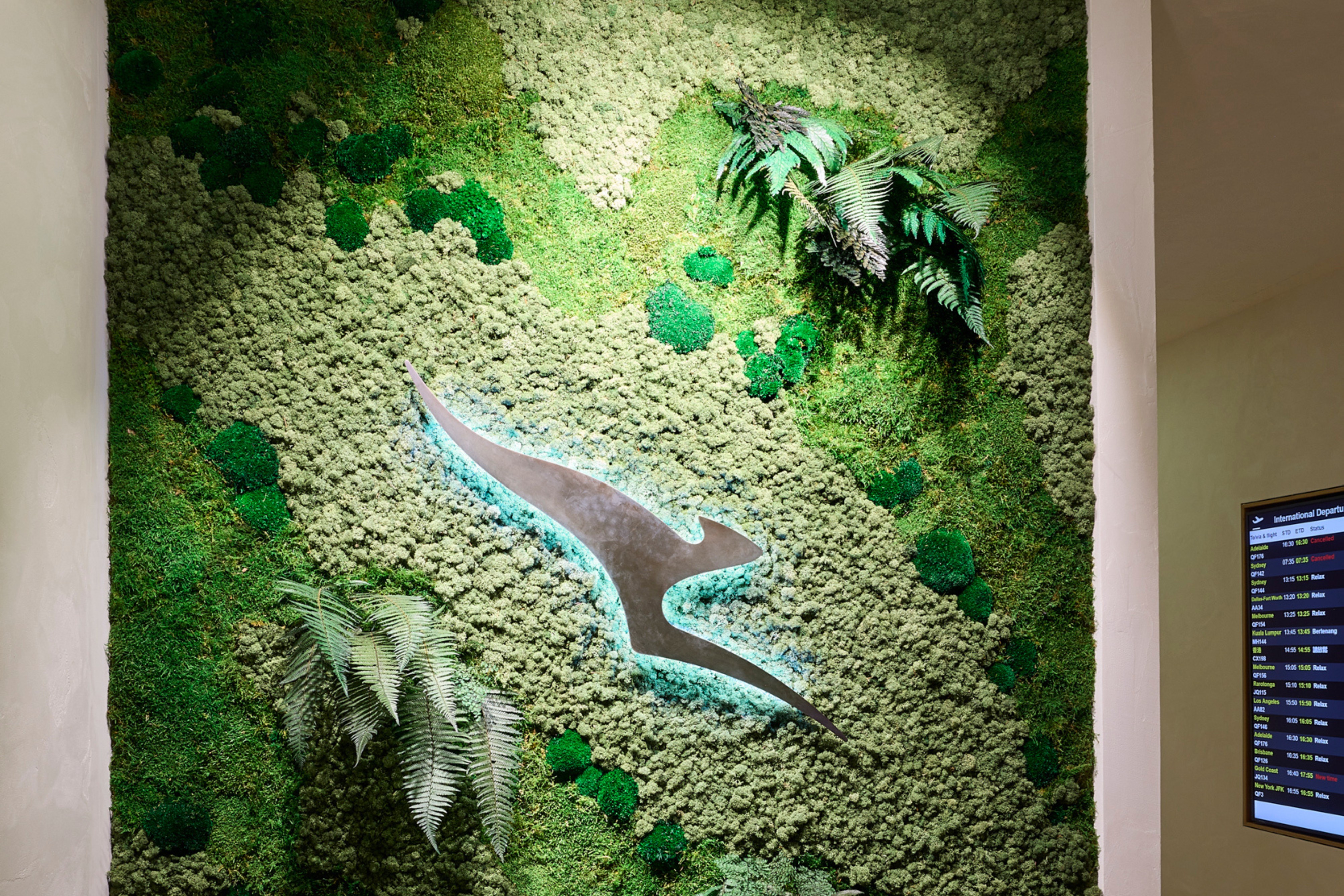 Green plant panel in the Qantas Business Lounge, Auckland — biophilic detail anchoring a refined seating environment.