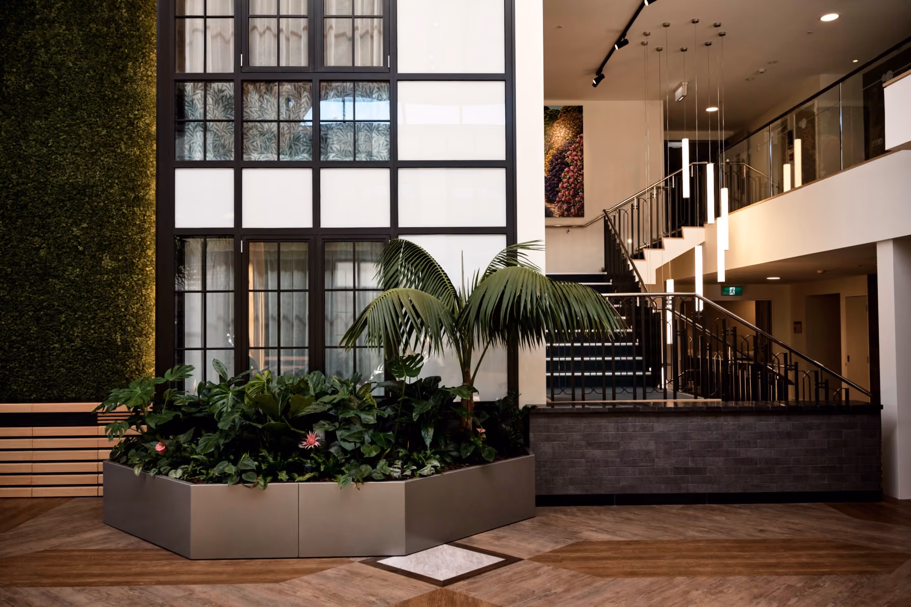 Hexagonal grey planters of bromeliads, calla lilies and ferns arranged as a seating cluster on timber flooring.